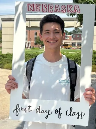 Yakub holding a Nebraska 'first day of class' frame on campus